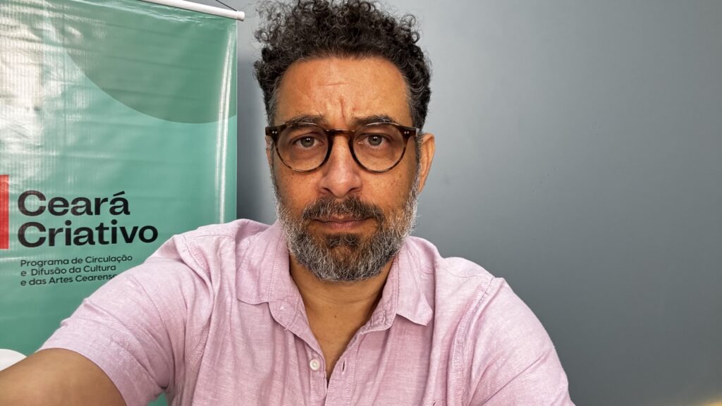 Felipe de Assis diante do painel do programa Ceará Criativo.